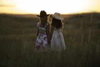 Girls with cowboy hats in field 