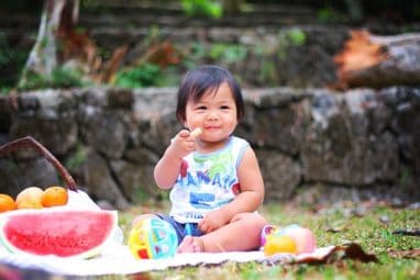 Baby eating a healthy snack at a picnic