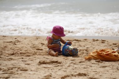 Baby playing with sand on beach
