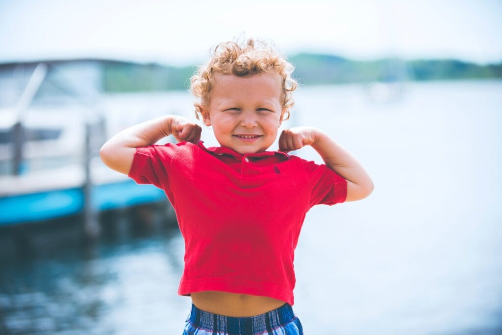 kid flexing muscles in front of lake