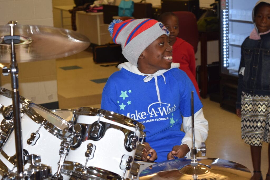 Make-A-Wish kid smiling and playing drums