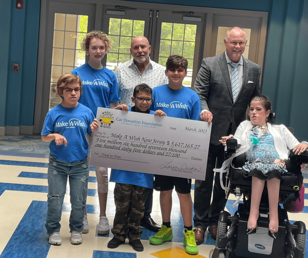 Wheels For Wishes executive handing check for over $5 million to Make-A-Wish New Jersey. 