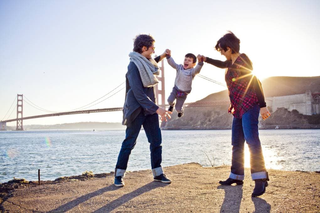 Family in Bay Area during sun set with Golden Gate Bridge in background.